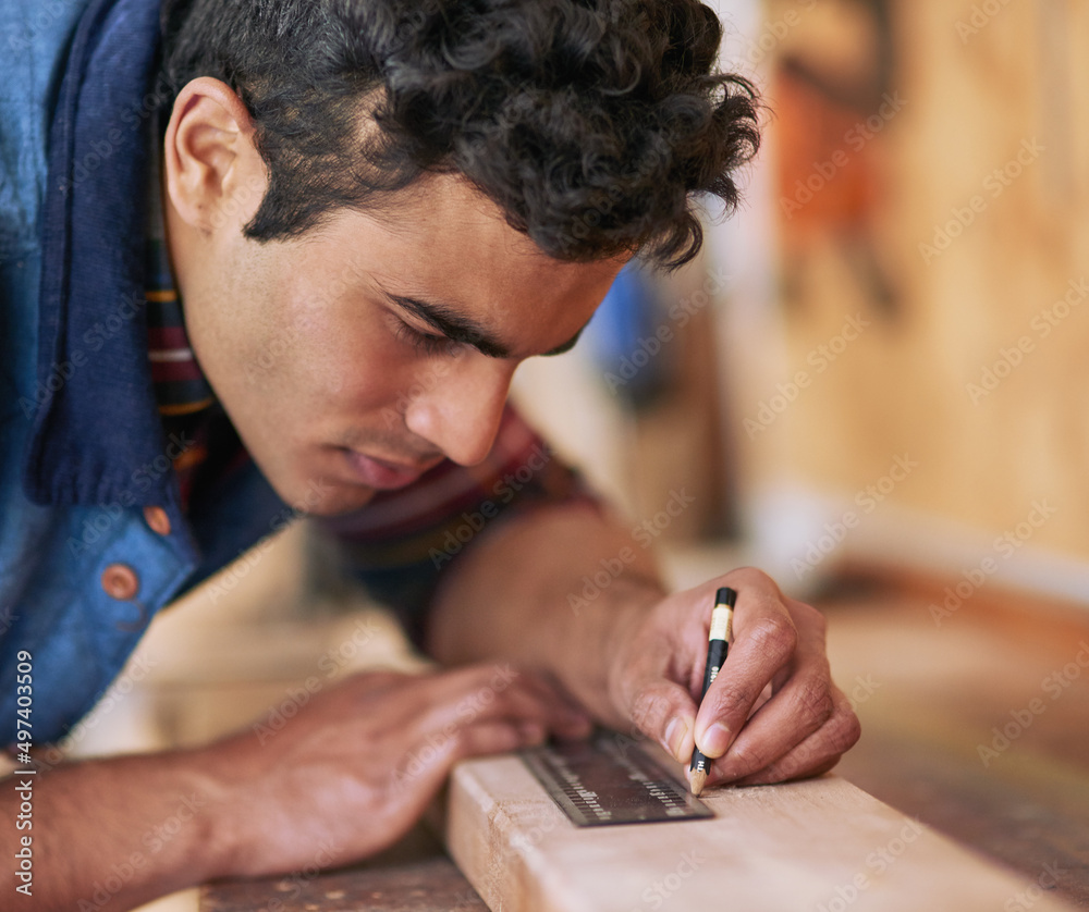 Canvas Prints Getting it right the first time. Shot of a focused handyman measuring a piece of wood while working in his workshop.