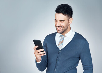Another text, another opportunity. Studio shot of a handsome young businessman using a cellphone against a grey background.