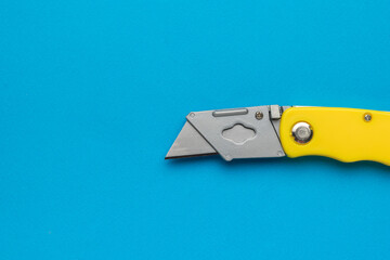 Unfolded folding knife cutter on a bright blue background. Flat lay.