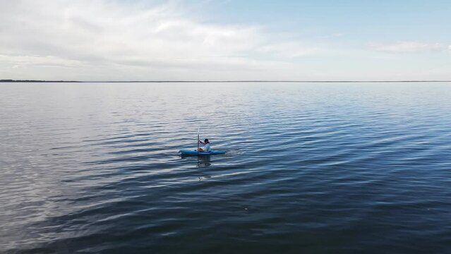 The magnificent clear blue water of buffalo lake, Alberta with a woman rowing in a kayak. Fast aerial parallax shot
