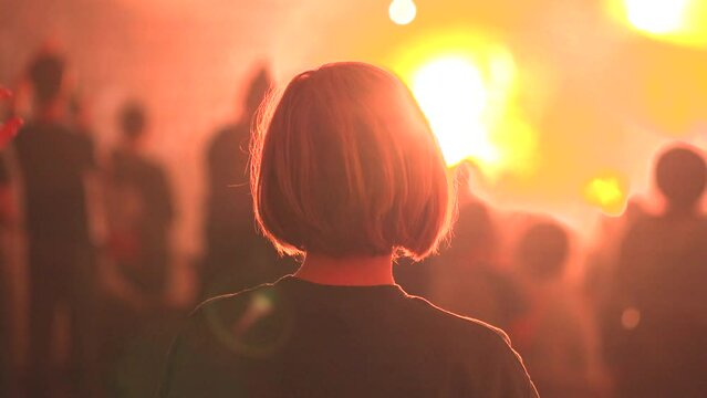 Hands raising at a concert with lights blaring as a woman rocks side to side