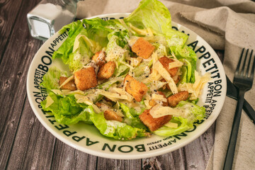 An exquisite traditional Caesar salad of lettuce, toasted bread and fine Parmesan cheese with a garlic aioli and olive oil in a bowl that says Bon Appetite in French.