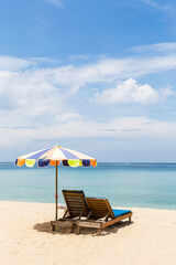 Wooden beach chair with colorful umbrella on sandy beach, summer holiday, outdoor day light, relaxing by the sea, vertical style