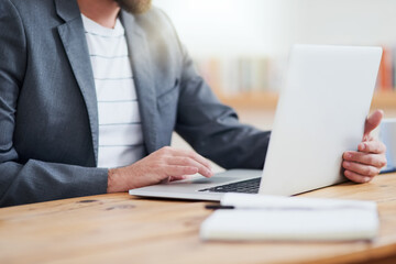 Its a matter of connectivity. Cropped shot of an unrecognizable businessman working on his laptop while sitting in the home office.