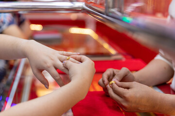 A customer comes to buy a ring and is trying to wear a ring on his finger.