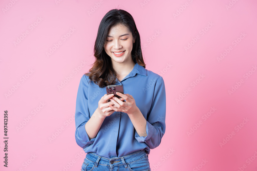 Wall mural image of young asian business woman using smartphone on pink background - Wall murals