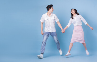 Full length image of young Asian couple on blue background - Powered by Adobe