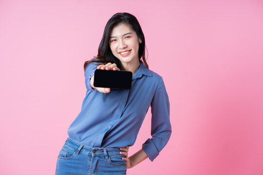 Image of young Asian business woman using smartphone on pink background