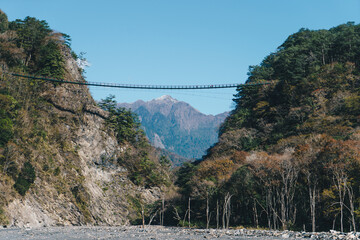 Nenggao mountain covered with snow and Aowanda Suspension Bridge above the riverbank of Wanda North Fork Hot Spring, Taiwan