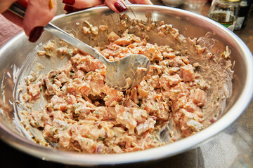 Chef stirs salmon dish in bowl with spoon