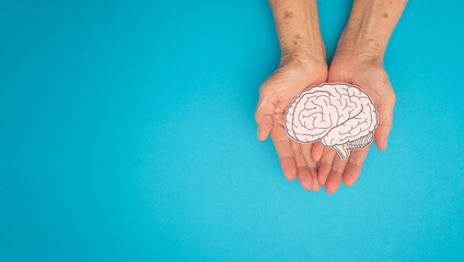 Brain shape made from paper on a palm senior woman on a blue background