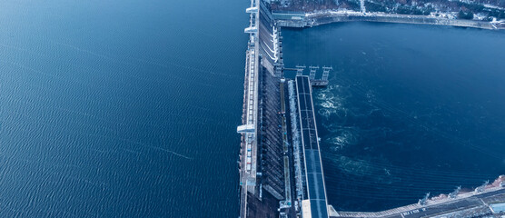 Aerial top view hydroelectric dam, water discharge through locks, blue color banner industrial...