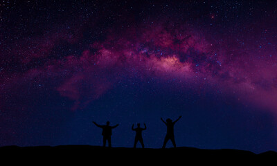Fototapeta premium A group of people are happily standing next to the Milky Way galaxy pointing at a bright star.