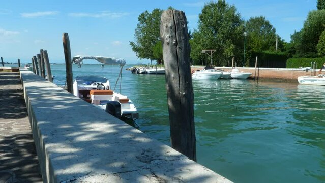 fantastic jetty  on a blue green sea  in Italy,  near Venice (canale portosecco), with little boats looked on the poles  all in all a a beautiful sunny summer day with blue sky pan