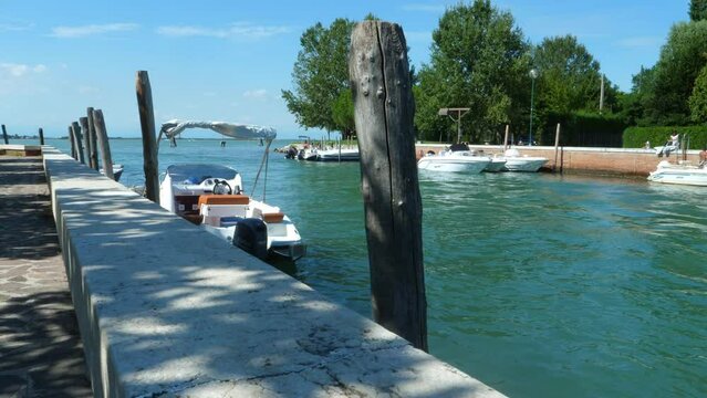beautiful little port, jetty on a blue green sea  in Italy,  near Venice (canale portosecco), with little boats  on the poles  all in all a a beautiful sunny summer day with blue sky pan