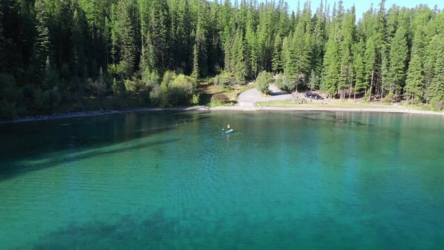 Isolated View Of A Man Stand-Up Paddling In Blue Calm Water At ashley lake in montana, United States. Aerial Shot