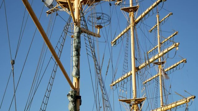 Tilting shot of three masts of tall ship boat hotel Alexander Von Humboldt in Bremen. No sails and clear blue skies behind. Yellow masts.View of quarterdeck and shrouds on the sides.