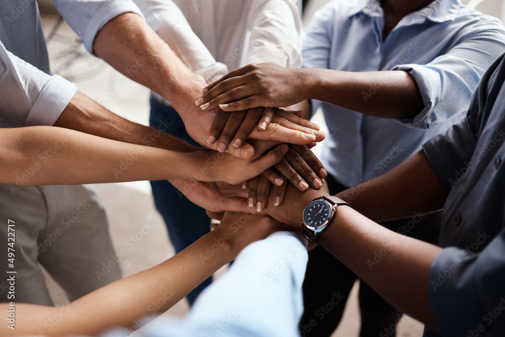 Poster were in this together. shot of a group of unrecognizable businesspeople stacking their hands at work