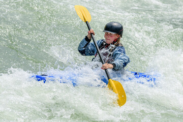 Junge Sportlerin hat Spass beim Kayaking im Wildwasser
