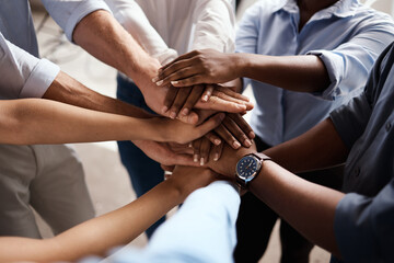 Were in this together. Shot of a group of unrecognizable businesspeople stacking their hands at...