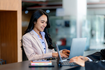 Beautiful Asian business woman sitting working on laptop in office.