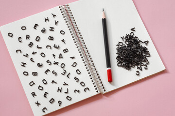 black latin letters randomly scattered on a blank page of a notebook, the concept of grammar, creativity in writing and journalism - obrazy, fototapety, plakaty