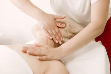 Massage and body care.  a mature woman receives a relaxing and toning facial and neck massage at the spa.