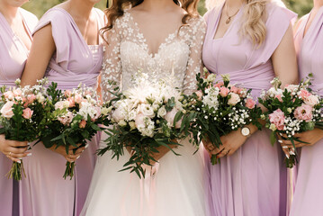 A luxurious wedding bouquet with white and pink peonies in the hands of the bride and bridesmaid...