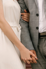 The bride and groom embrace, hands close-up