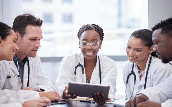 Take A Look At This. Cropped Shot Of A Group Of Young Doctors Looking At A Tablet During A Meeting In The Hospital Boardroom.