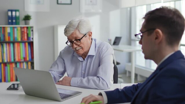 Sales manager consult aged client showing education program on laptop