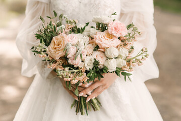 A luxurious wedding bouquet in the shape of a heart in the hands of the bride