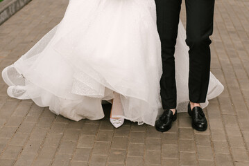 Obraz na płótnie Canvas Close-up photo of the legs of the bride and groom, stylish shoes for the wedding