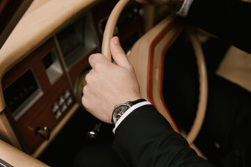 Details of the groom, male hands on the steering wheel of a retro car