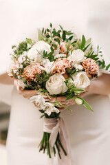 A luxurious wedding bouquet with white roses in the hands of the bride
