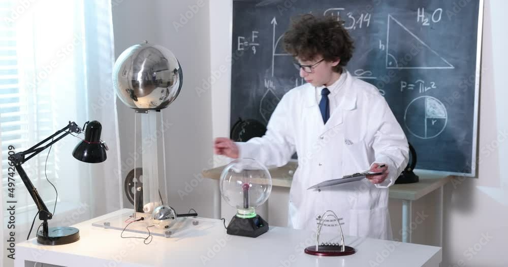 Wall mural schoolboy experimenting in physics class. young student doing physics experiment in the classroom