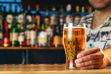 Barman serves glass of cold beer at bar counter in pub