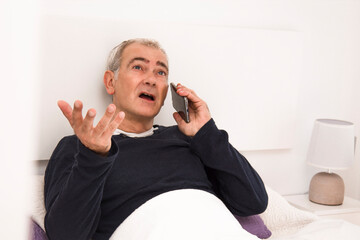 man in bed talking on mobile or cell phone