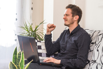 exultant and euphoric young man with laptop at home