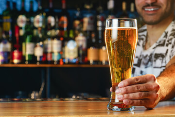 Barman serves glass of cold beer at bar counter in pub