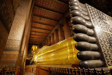 Fototapeta premium The giant reclining Buddha golden statue is seen in Wat Pho temple complex, also known as Wat Phra Chetuphon, Bangkok, Thailand.
