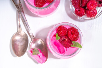 Raspberry panna cotta dessert with fresh raspberries and lemon balm mint leaves. Pink panna cotta...