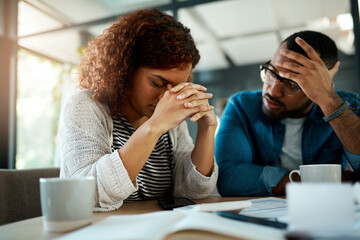 It feels like were starting to drown in debt. Shot of a young couple looking stressed out while working on their budget at home.