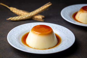 Cream caramel pudding with caramel sauce in plate on white rustic table