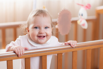 Portrait of a happy and laughing toddler girl in a crib