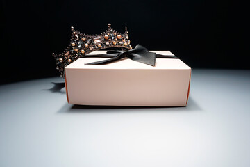 Gift box with a crown , with a black ribbon on gray background, holiday sale