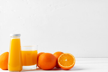 Glass bottle of orange juice with orange fruit on white background