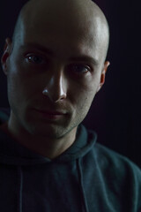 Portrait of a young bald man in the dark with a serious and scary look
