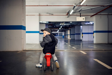 A little boy learning traffic rules on a tricycle in underground garage.