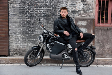 Plakat Biker with modern motorcycle having a break in the city.